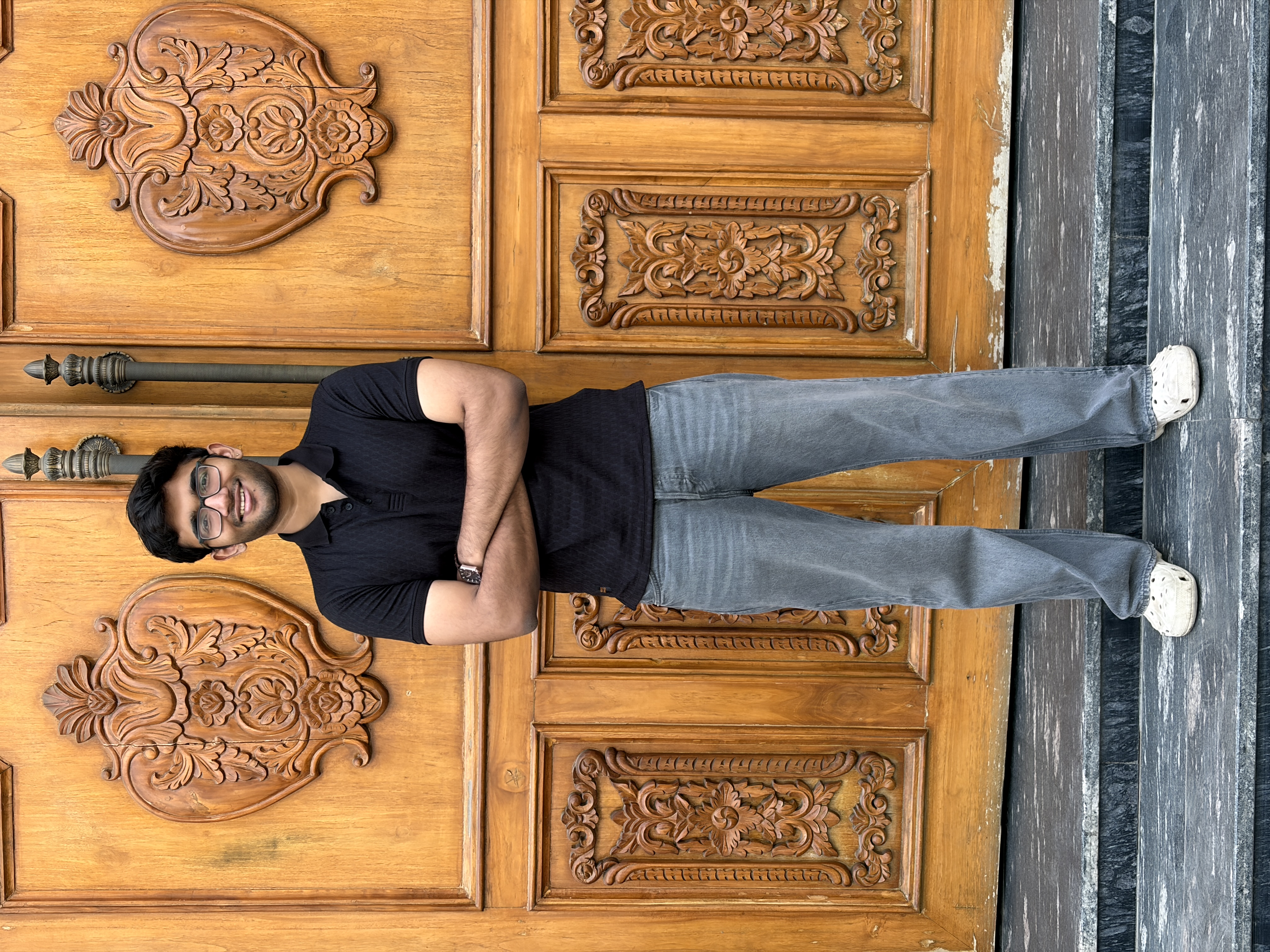 Suraj Mundhada smiling, wearing glasses and a black polo